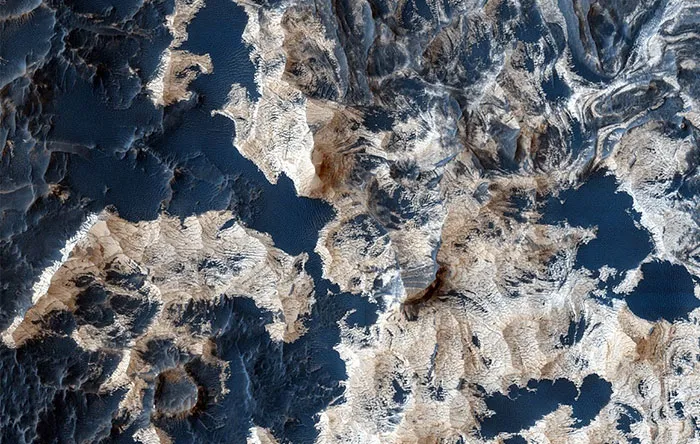 کف دهانه Schiaparelli از شن پوشیده است. شنهایی که در این تصویر به رنگ آبی تیره نمایش داده شدهاند. بهمرور زمان باد لایههای نازک این قسمت را حرکت داده و سنگ بستر این منطقه به نمایش درآمده است.