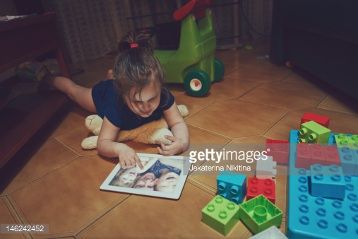 دختری که روی تبلت عکس نگاه می‌کند