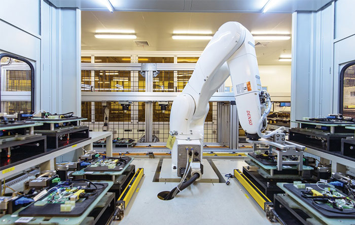 یک بازوی روباتیک بوردهای الکترونیکی را برای آزمایش در کارخانه‌ی CIG جابجا می‌کند. قبلا این کار دستی انجام می‌شد.