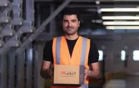 از کارکنان مرکز پردازش که جعبه دیجی‌کالا را در دست دارد