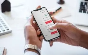 یک دست مردانه که گوشی دارد و در صفحه نمایش قیمت کالای محصولات دیجی کالا نمایش داده شده است