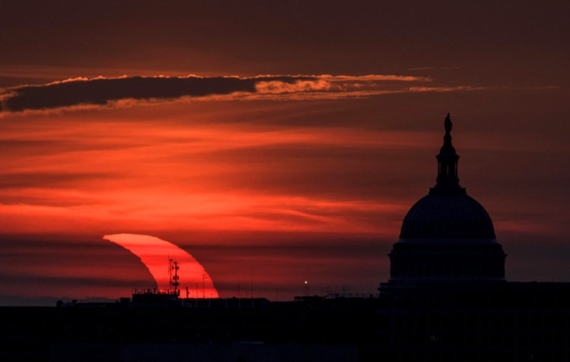 تصویری از طلوع خورشید نیمه در کنار کاخ کنگره‌ی آمریکا در واشنگتن