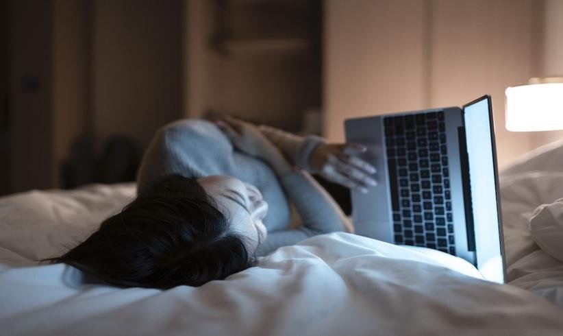 زنی به جای خوابیدن در تخت با لپتاپ کار می‌کند