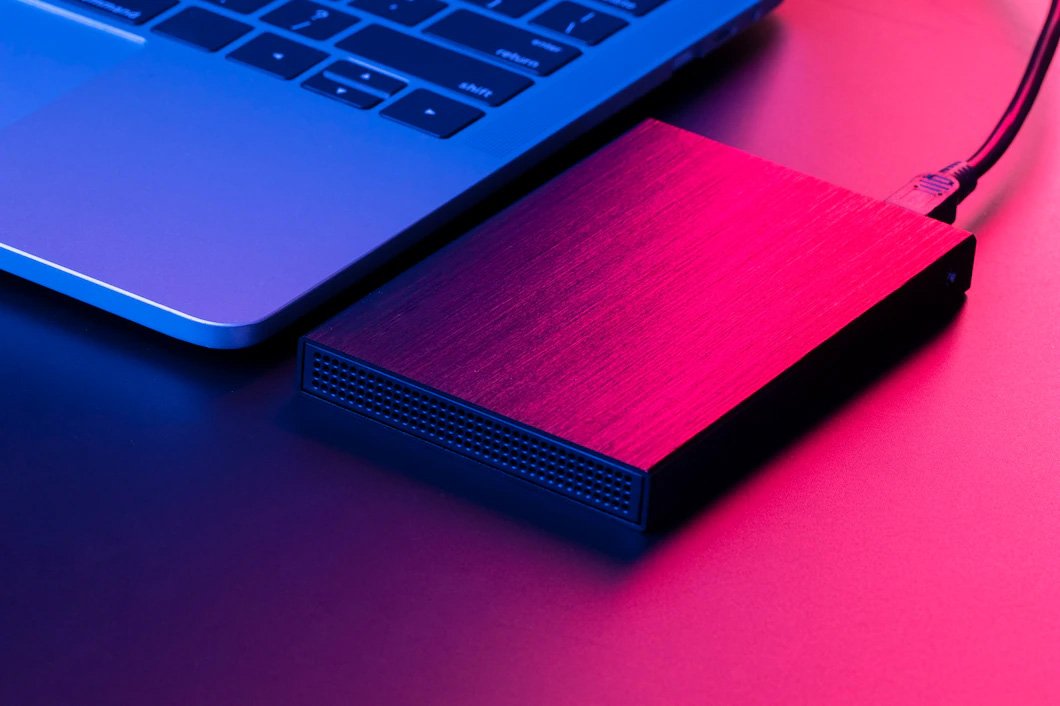 هارد اکسترنال مقاوم به لپ تاپ متصل است و در نور سرخ و آبی دیده می‌شود