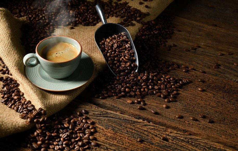 یک فنجان قهوه در کنار دانه‌های قهوه