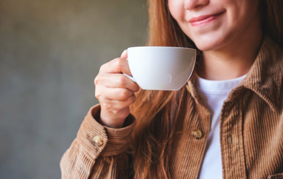یک زن که یک فنجان قهوه در دست دارد
