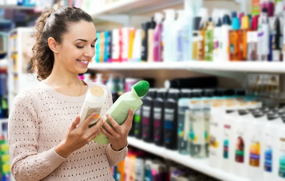 یک زن در فروشگاه مشخصات 2 شامپوی مختلف را مقایسه میکند