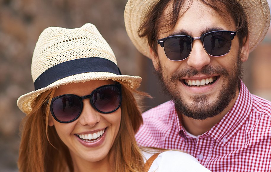 یک زوج جوان در تعطیلات با کلاه حصیری و عینک آفتابی