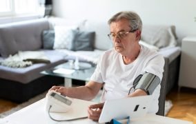 مردی در حال استفاده از دستگاه فشار سنج خانگی