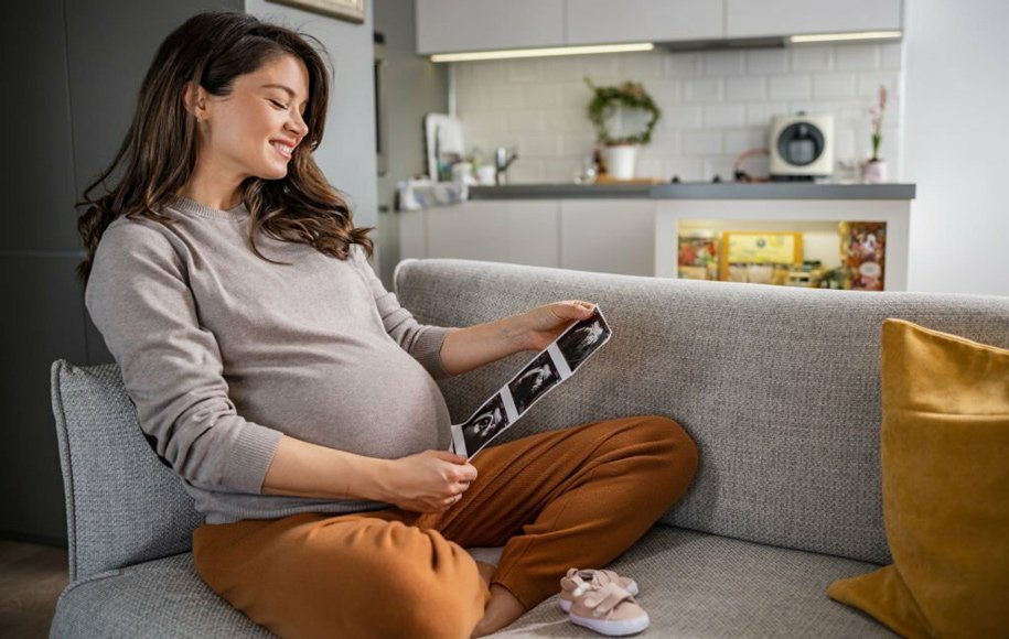 یک زن باردار که به عکس سونوگرافی جنین نگاه می‌کند