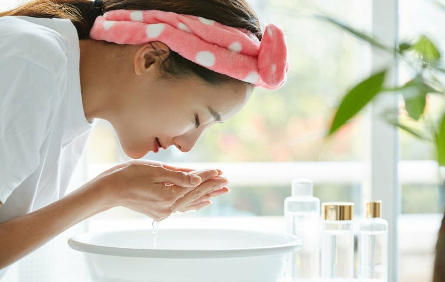 یک زن در حال شستن صورت خود است