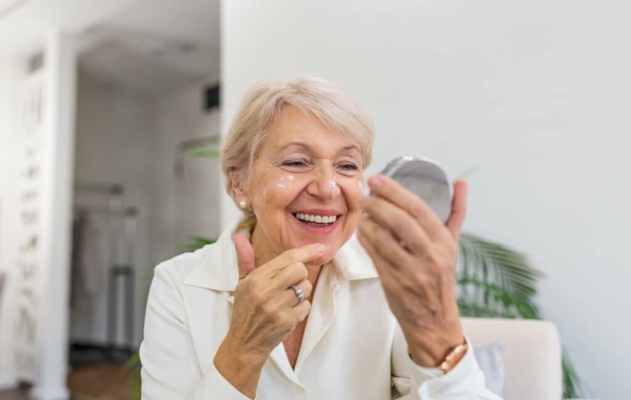 یک زن مسن که روی صورت خود مرطوب‌کننده می‌زند