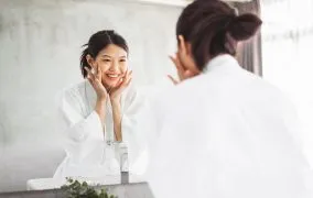 زنی در حال شست‌وشوی صورت خود است.