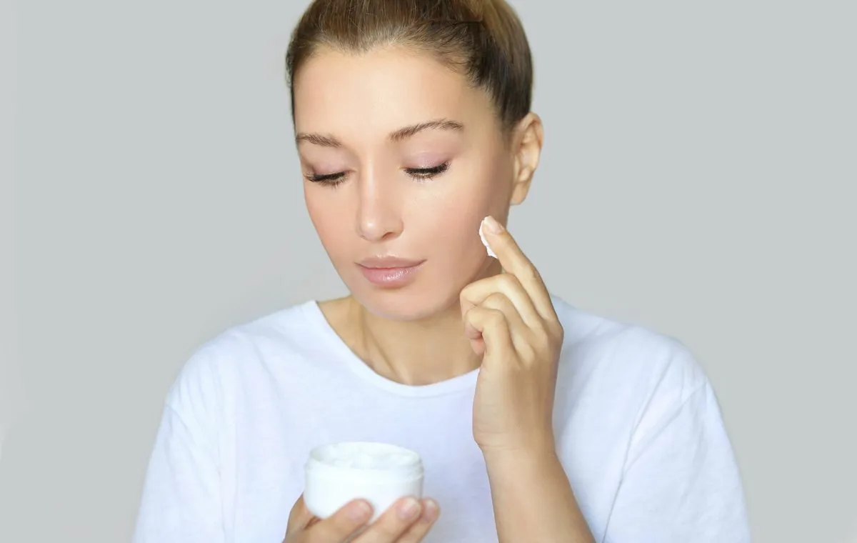 یک زن جوان که یک قوطی کرم در دست دارد