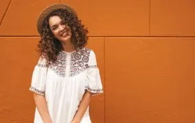 دختر جوانی با استایل بوهو در یک پس زمینه‌ی نارنجی