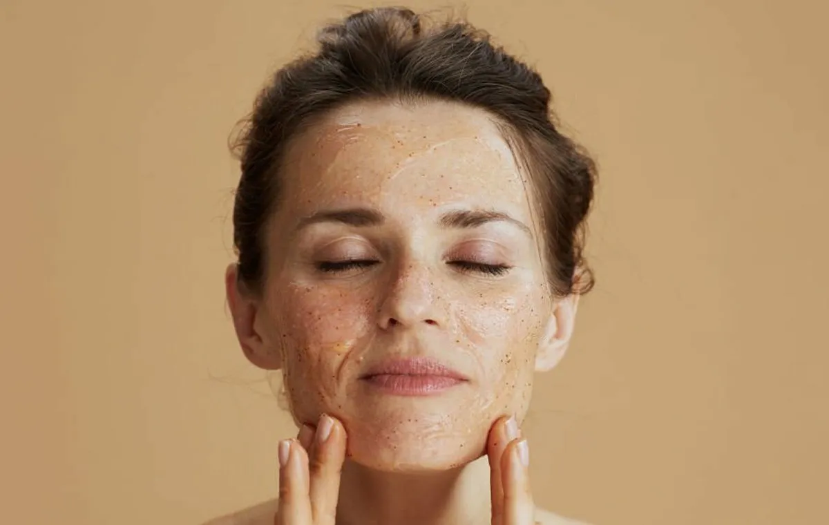 یک زن با چشم‌های بسته که روی صورت خود لایه‌بردار زده است