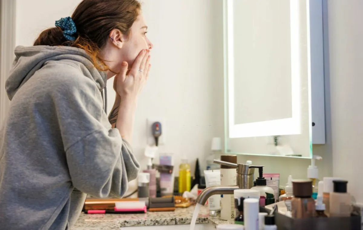 زنی که روبه‌روی آینه ایستاده و به صورت خود نگاه می‌کند