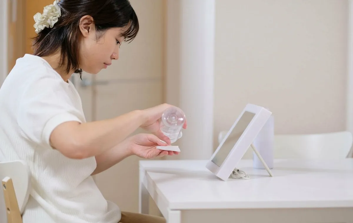 یک زن که پشت میز نشسته و مقداری تونر روی پد می‌ریزد