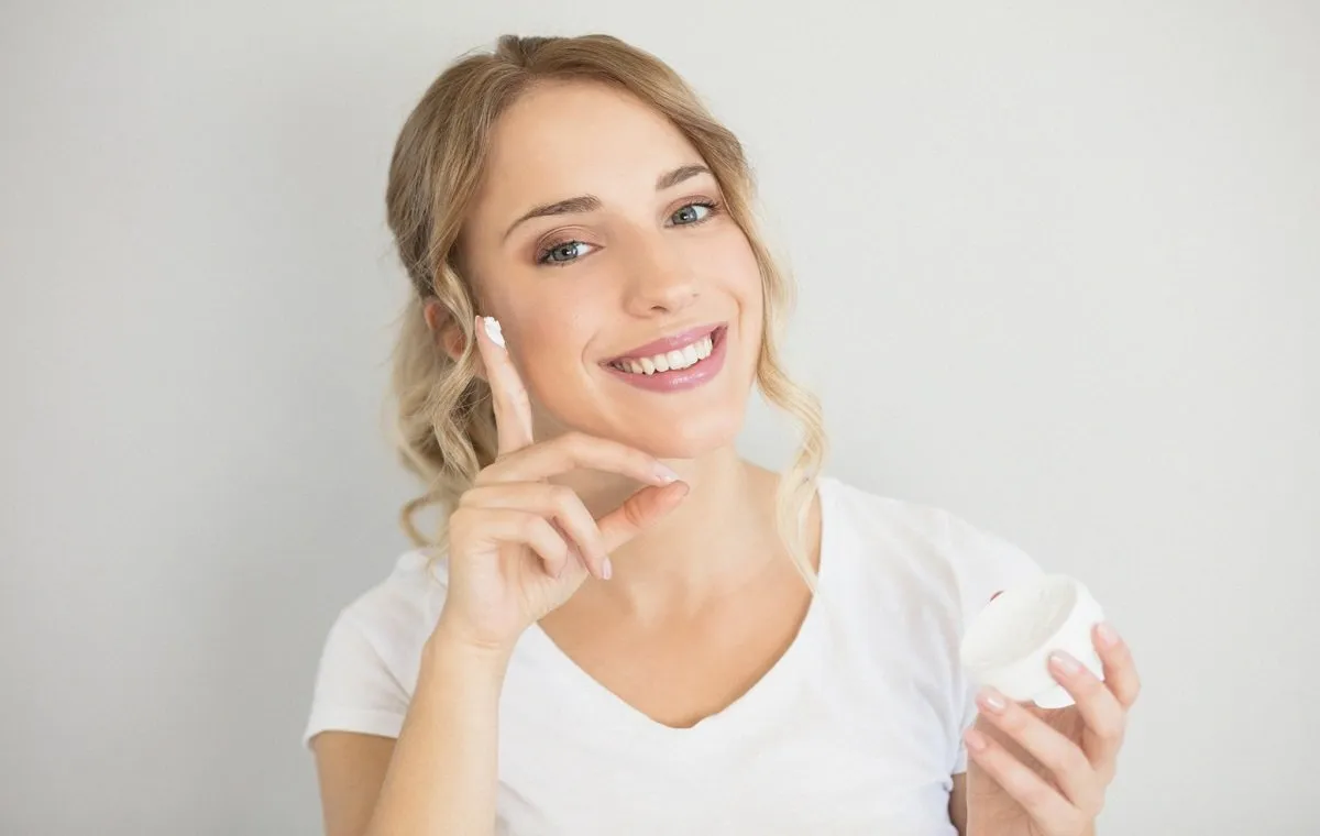 یک زن جوان که یک قوطی کرم شب در دست دارد و لبخند می‌زند