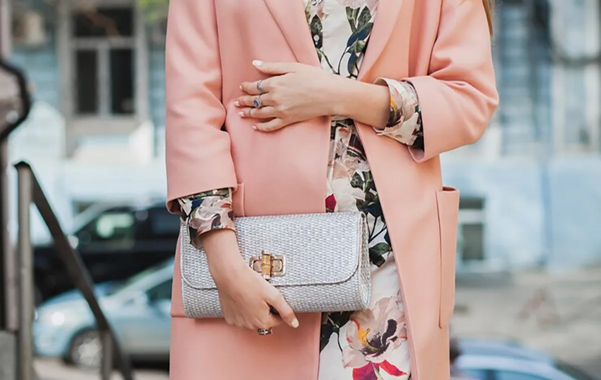 زنی با کت صورتی و یک کیف کلاچ