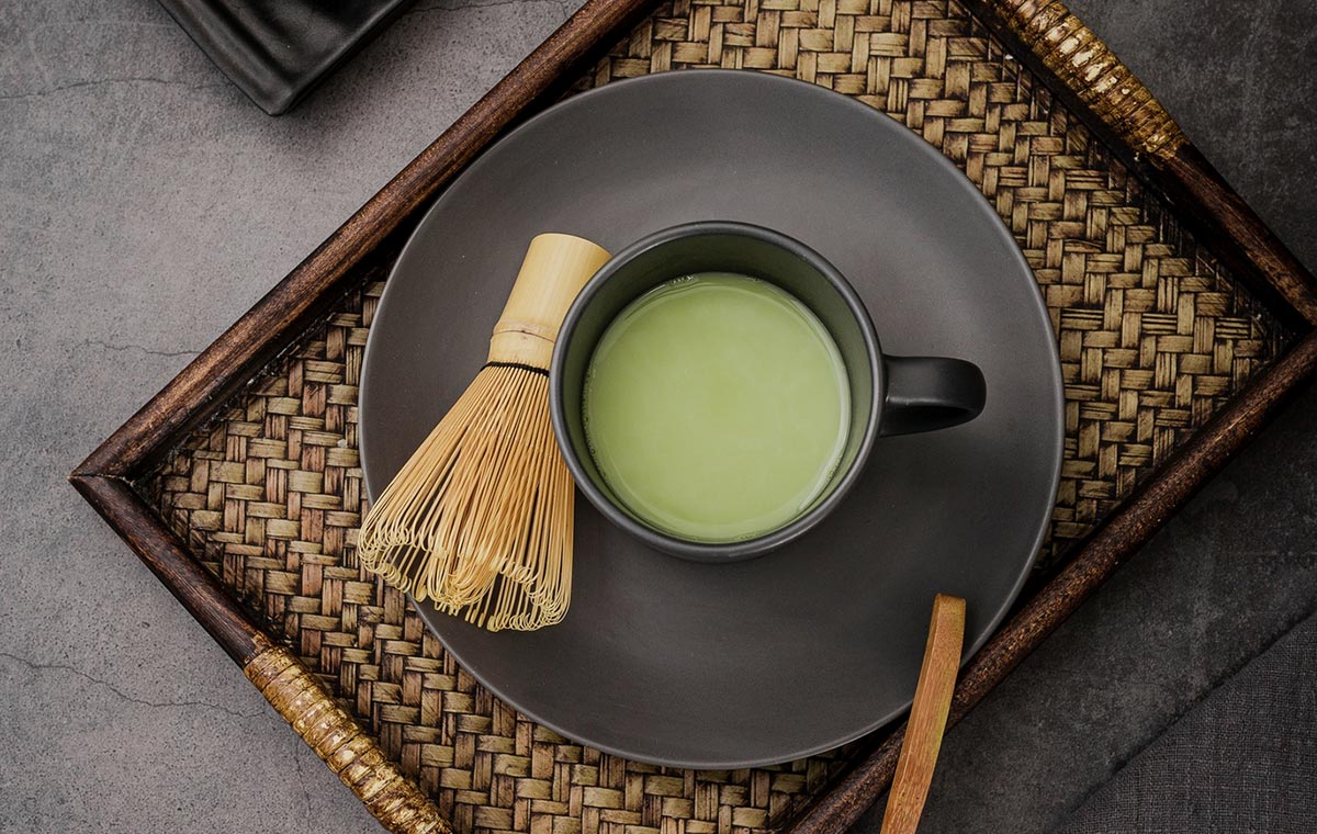یک فنجان از چای ماچا در کنار ابزار قدیمی ژاپنی