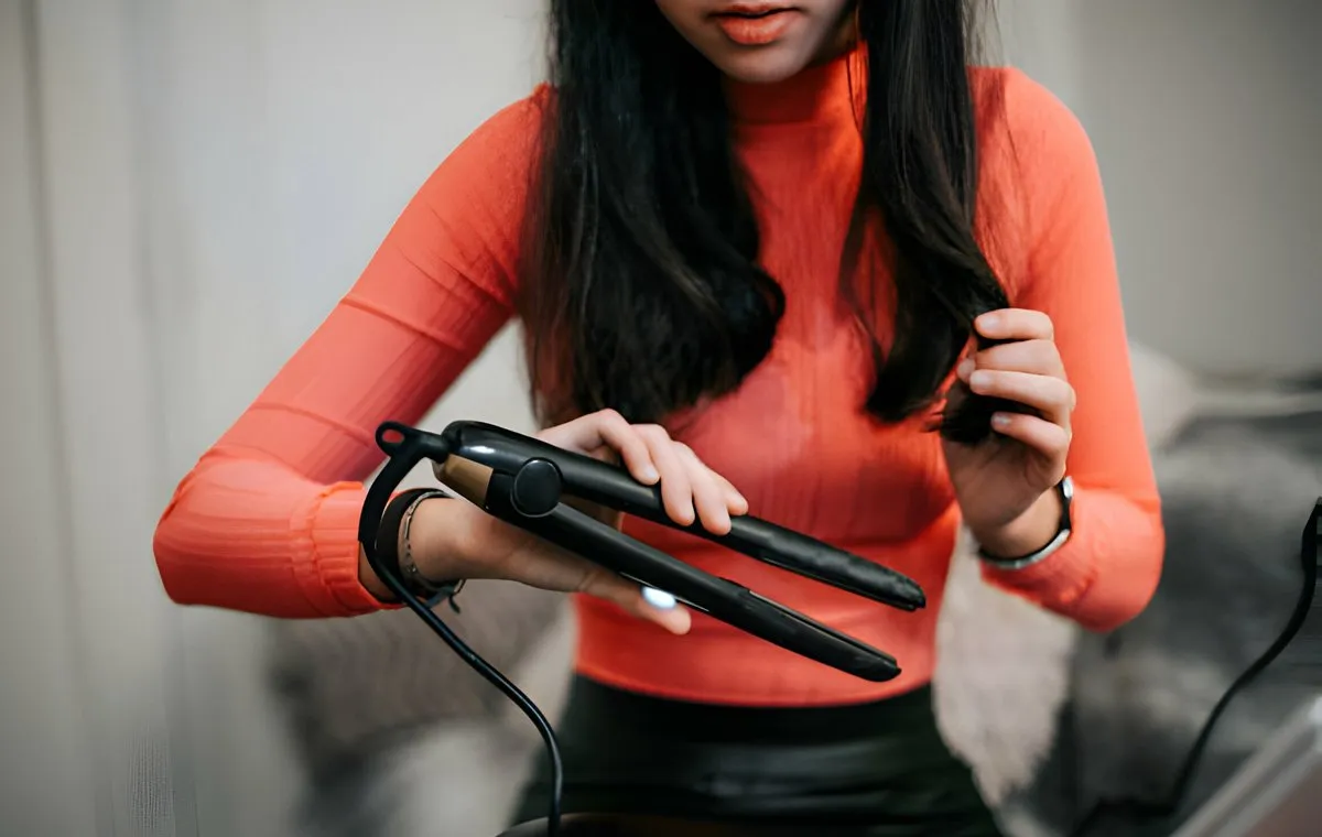 یک زن که موهای خود را با اتو صاف میکند