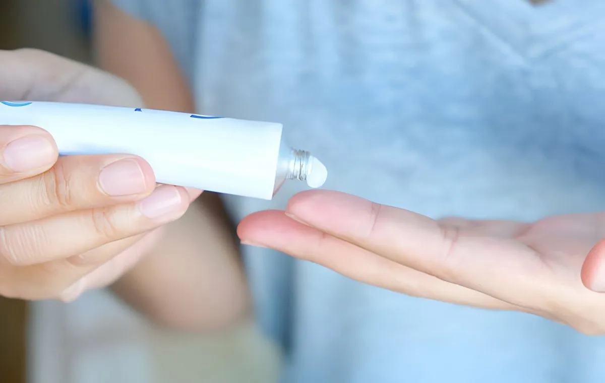 فردی که مقدار کمی پماد ضد درد روی انگشت خود می‌مالد