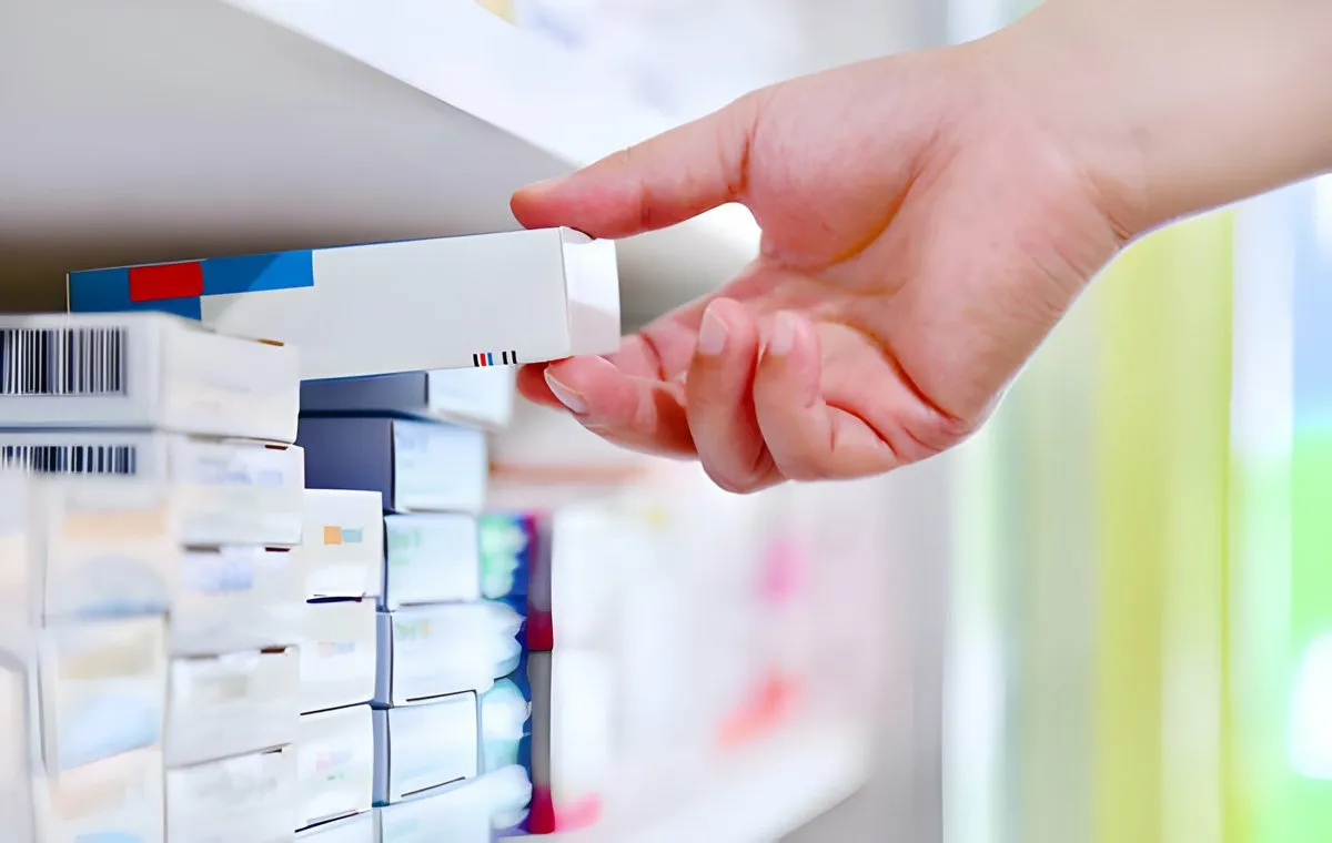 یک نفر یک بسته دارو از قفسه داروخانه برمی‌دارد
