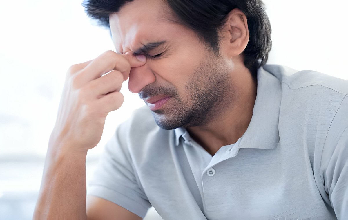 یک مرد جوان که به دلیل سردرد درد چشم‌های خود را بسته و بینی خود را با انگشت‌هایش می‌فشارد