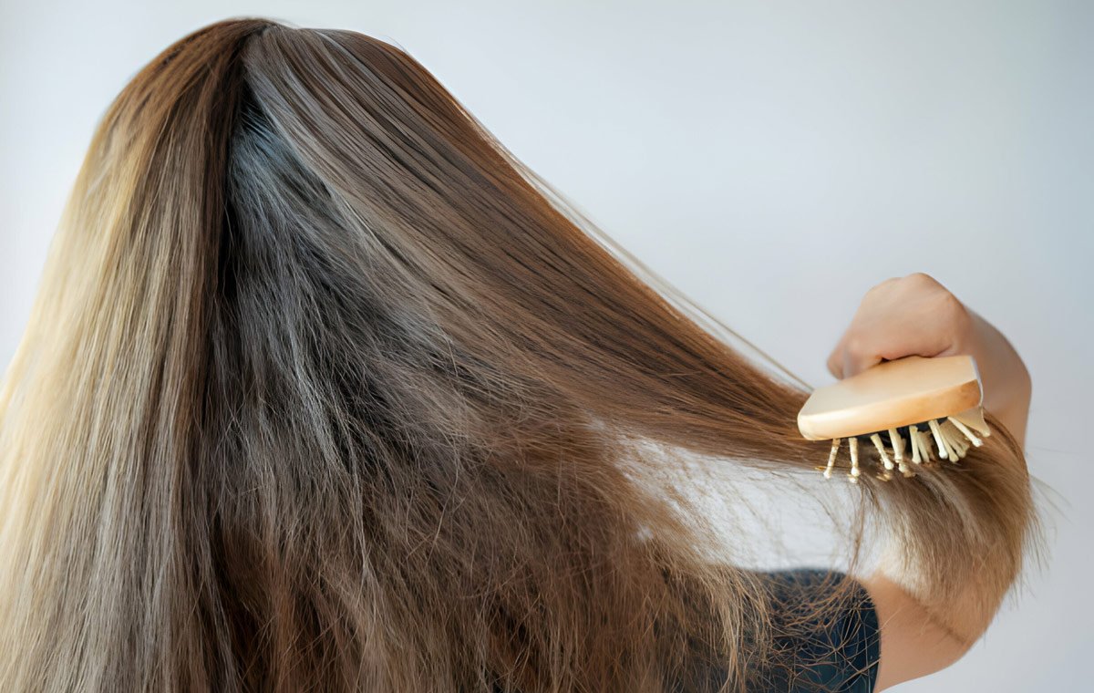 یک زن جوان که موهای خود را برس می‌زند