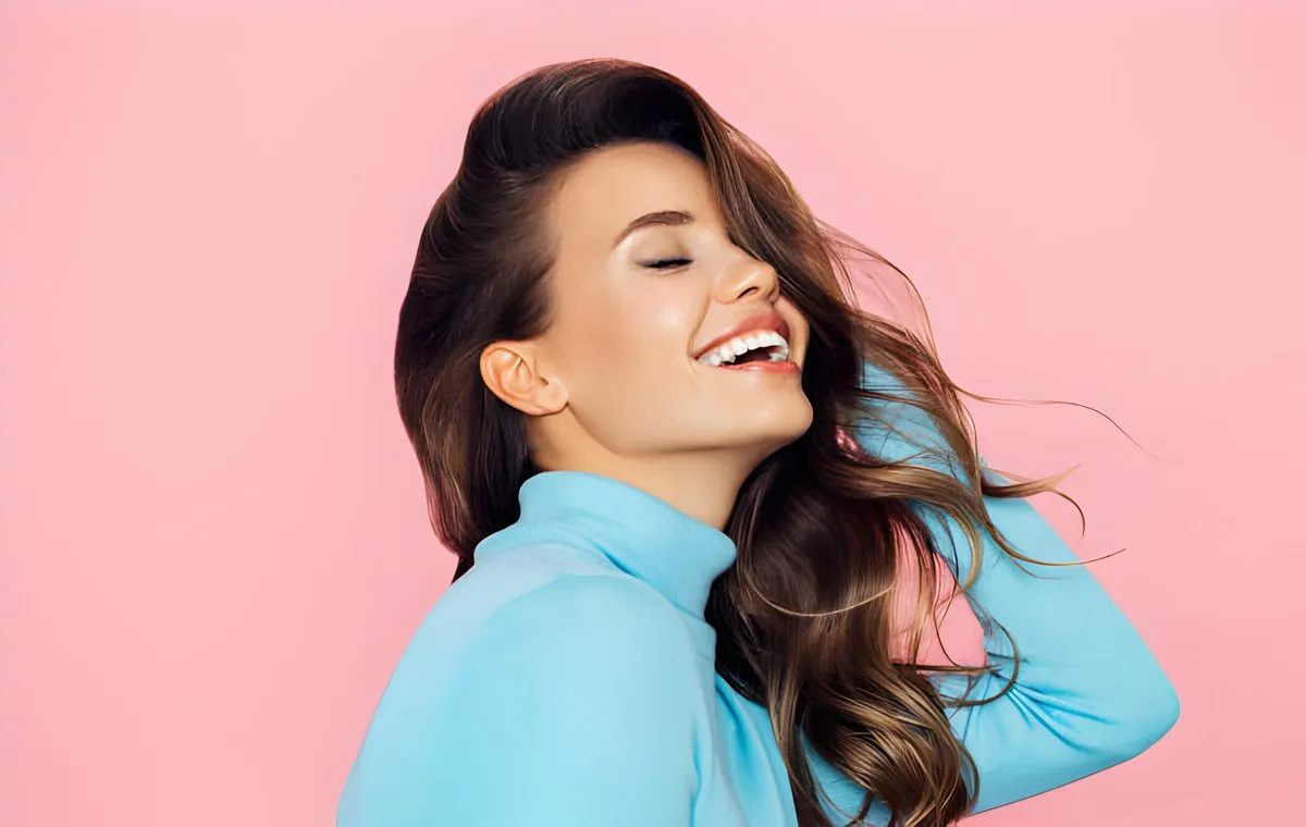 یک زن جوان که دست‌ها را در میان موهایش برده است و می‌خندد