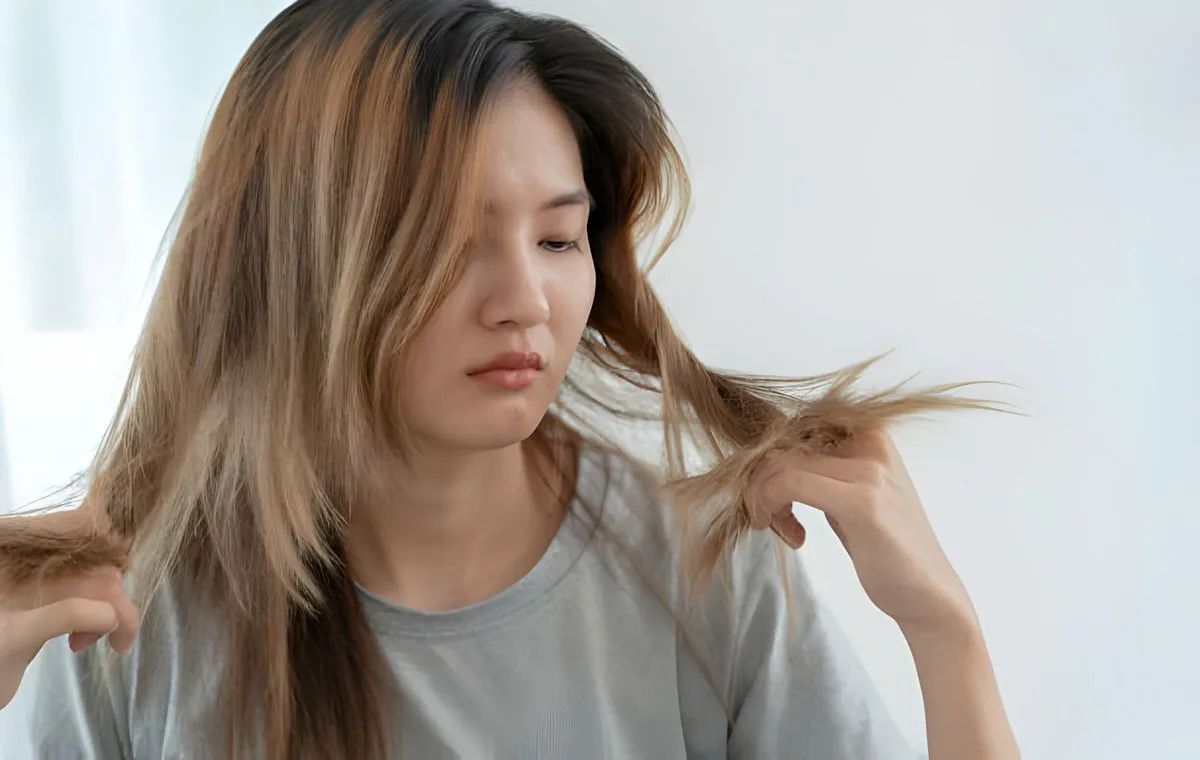 یک زن جوان که تکه‌ای از موهای خود را گرفته است و به آن نگاه می‌کند