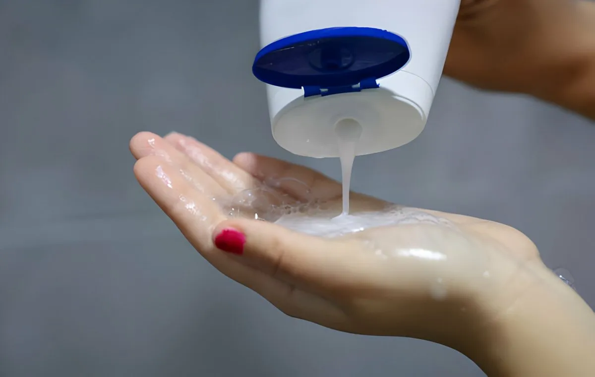 یک زن که شامپو را روی کف دست خود می‌ریزد