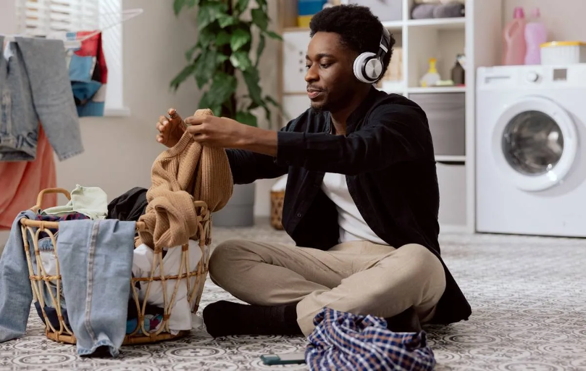 مردی در حال جمع‌آوری لباس‌های شسته شده
