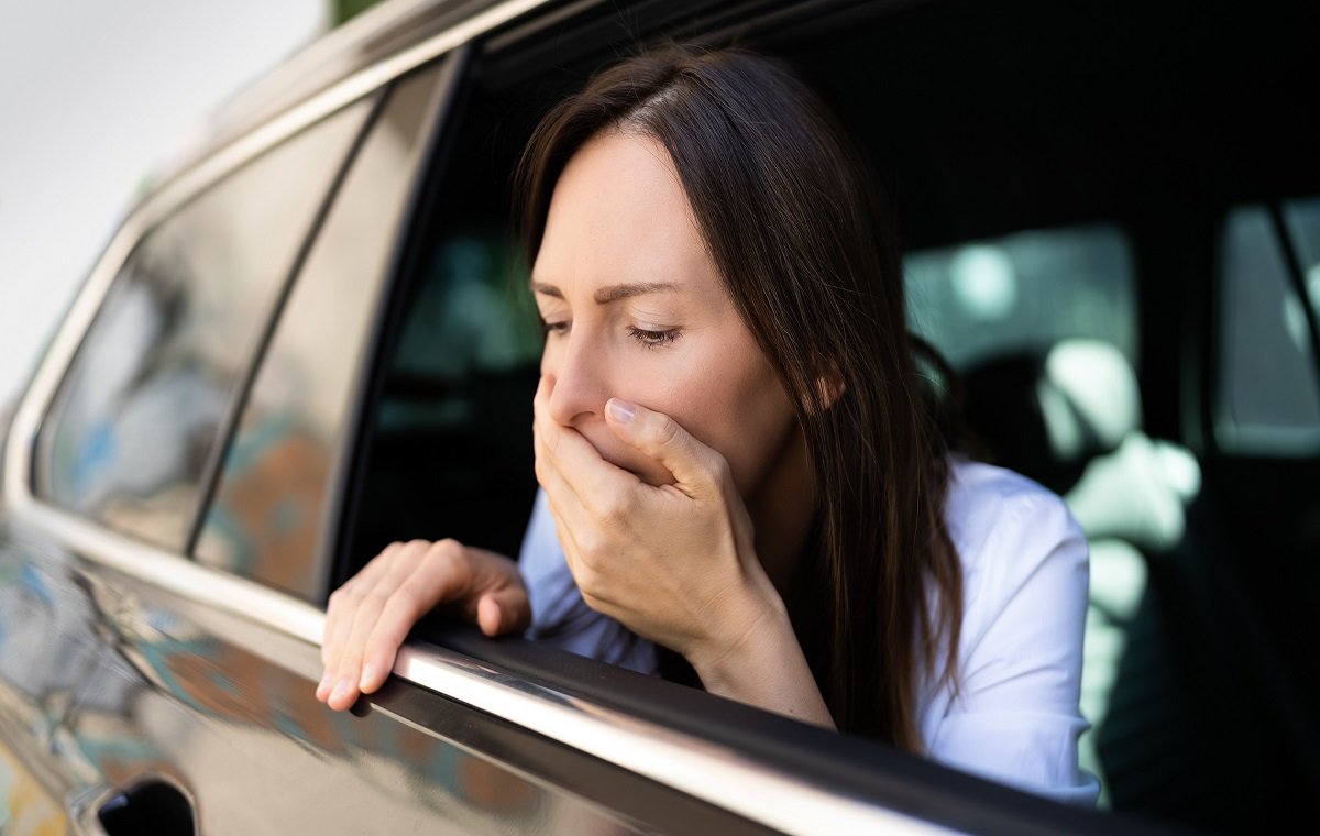 یک خانم سر شرا از شیشه ماشین بیرون آورده و دچار حالت تهوع در ماشین است