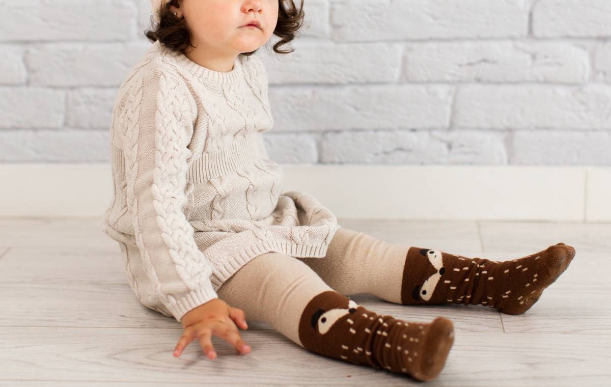 کودکی با جوراب قهوه‌ای نشسته است.