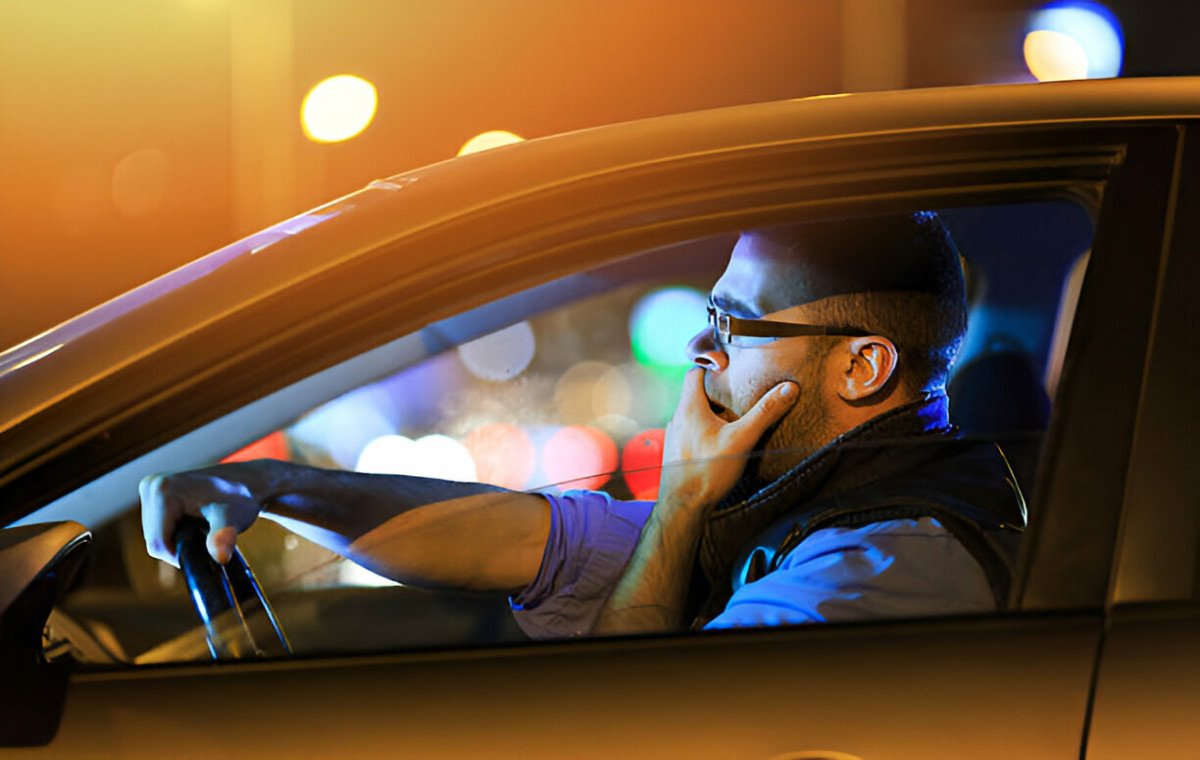 یک مرد جوان که عینک زده است و در شب رانندگی می‌کند