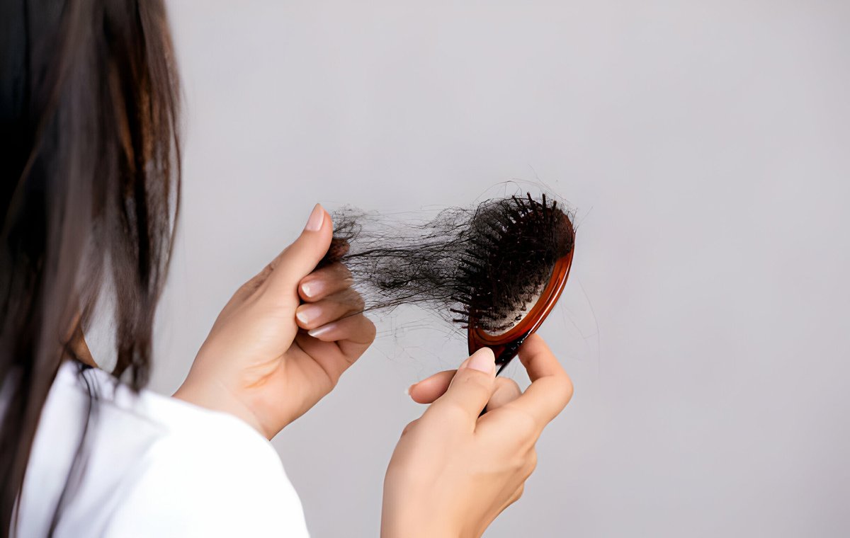 یک زن موهای خود را از برس جدا می‌کند