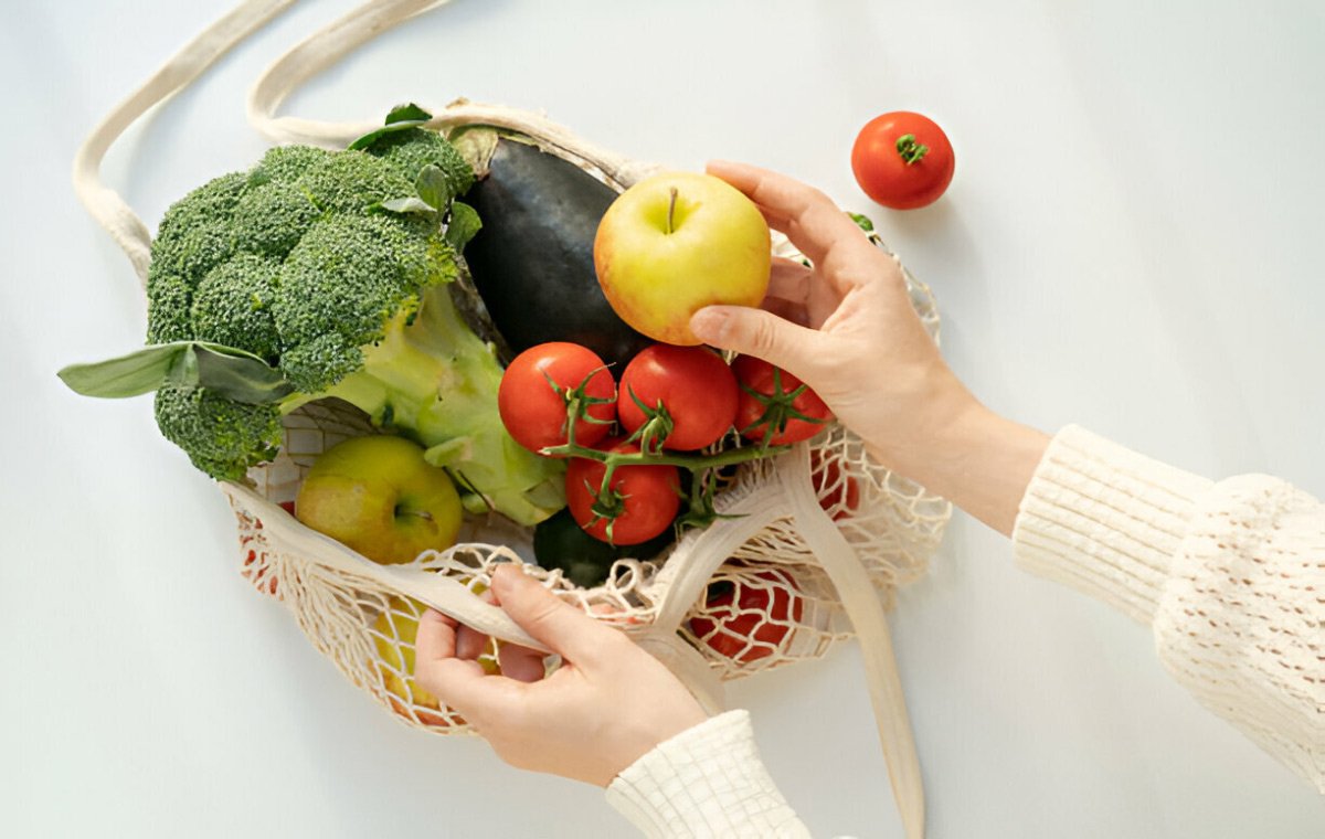 یک نفر میوه‌ها و سبزیجات را از کیسه خرید خارج می‌کند