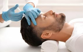 یک پزشک که آموزش مزوتراپی مو دیده است، محلول دارویی را به سر مرد جوان تزریق می‌کند