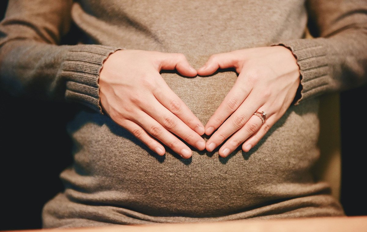 یک زن باردار که دست‌ها را روی شکم قرار داده است