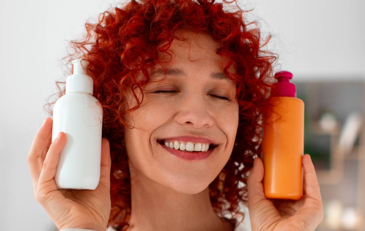 زنی با موهای فرفری قرمز و دو شامپو و نرم‌کننده‌‌ی مو