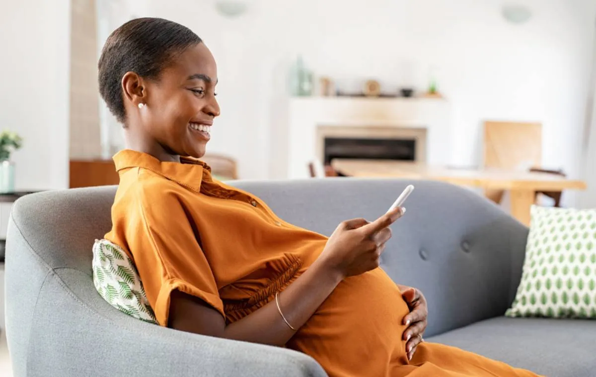 یک زن باردار روی مبل نشسته است