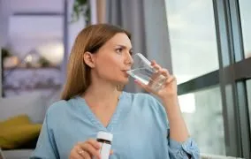 یک زن جوان در حال خوردن مکمل