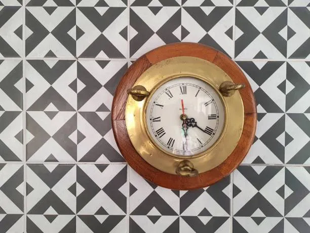 Antique bronze maritime clock on a modern wall.