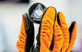 کارت حافظه اسامی مردم در مأموریت ناسا آرتمیس 1، توسط یک دست که دستکش نارنجی دارد به نمایش گذاشته شده است.