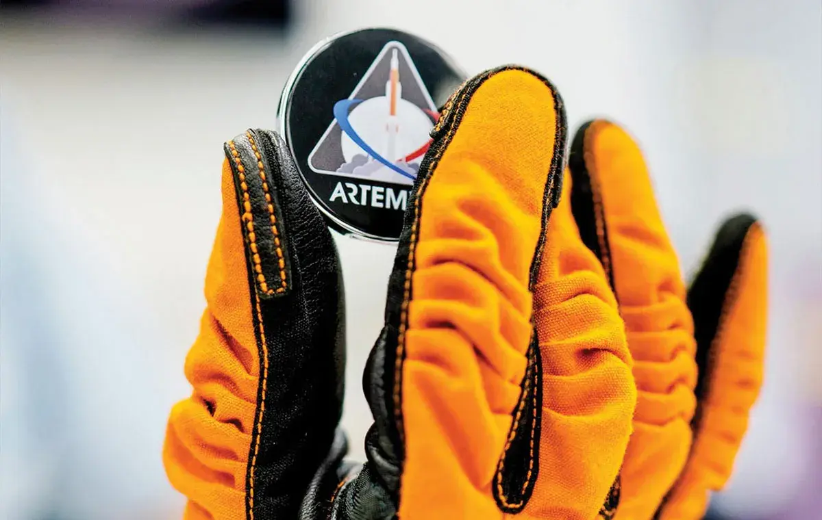 کارت حافظه اسامی مردم در مأموریت ناسا آرتمیس 1، توسط یک دست که دستکش نارنجی دارد به نمایش گذاشته شده است.